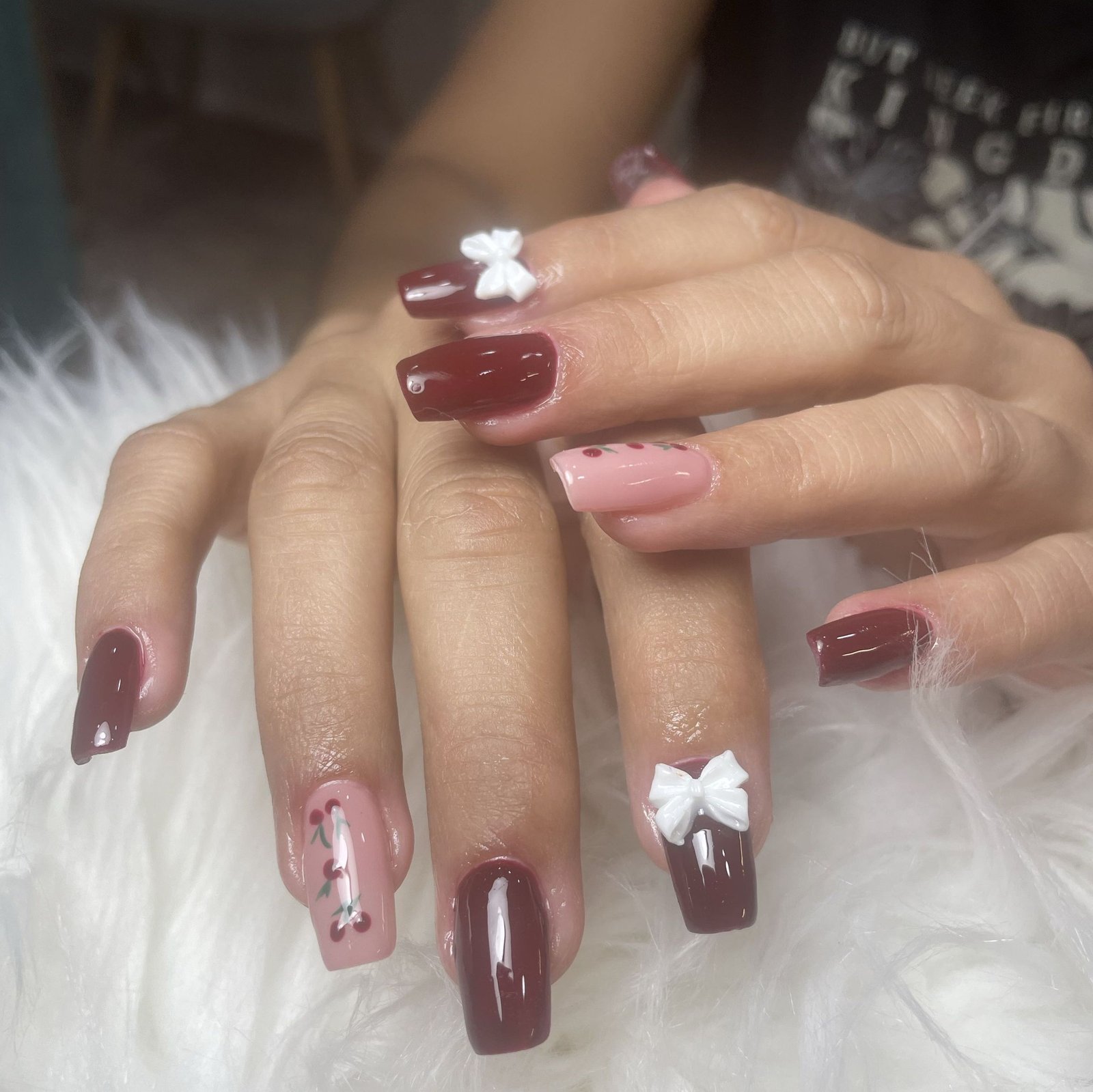 Extensiones de uñas burdeos con lazos 3D y cerezas
